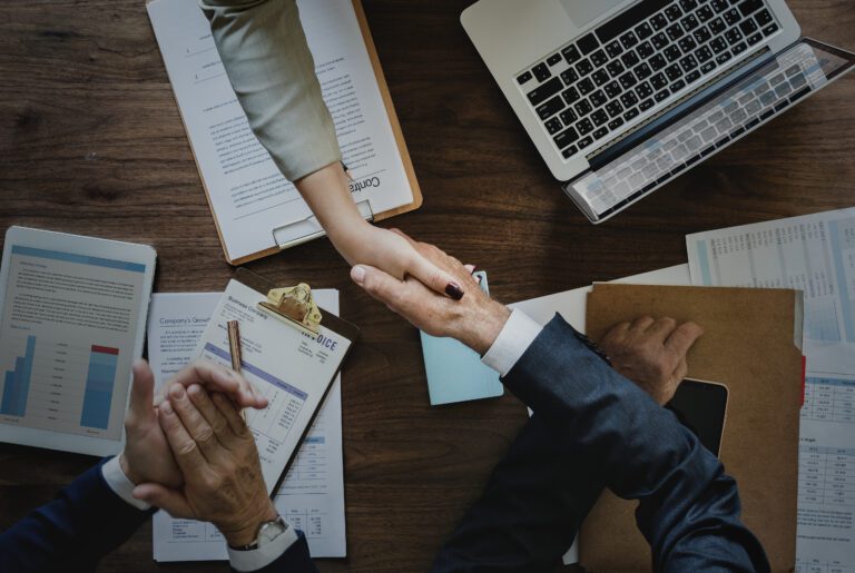 Business professionals shaking hands over company incorporation documents, symbolizing successful business registration and corporate setup services by B-Wiz Partners.