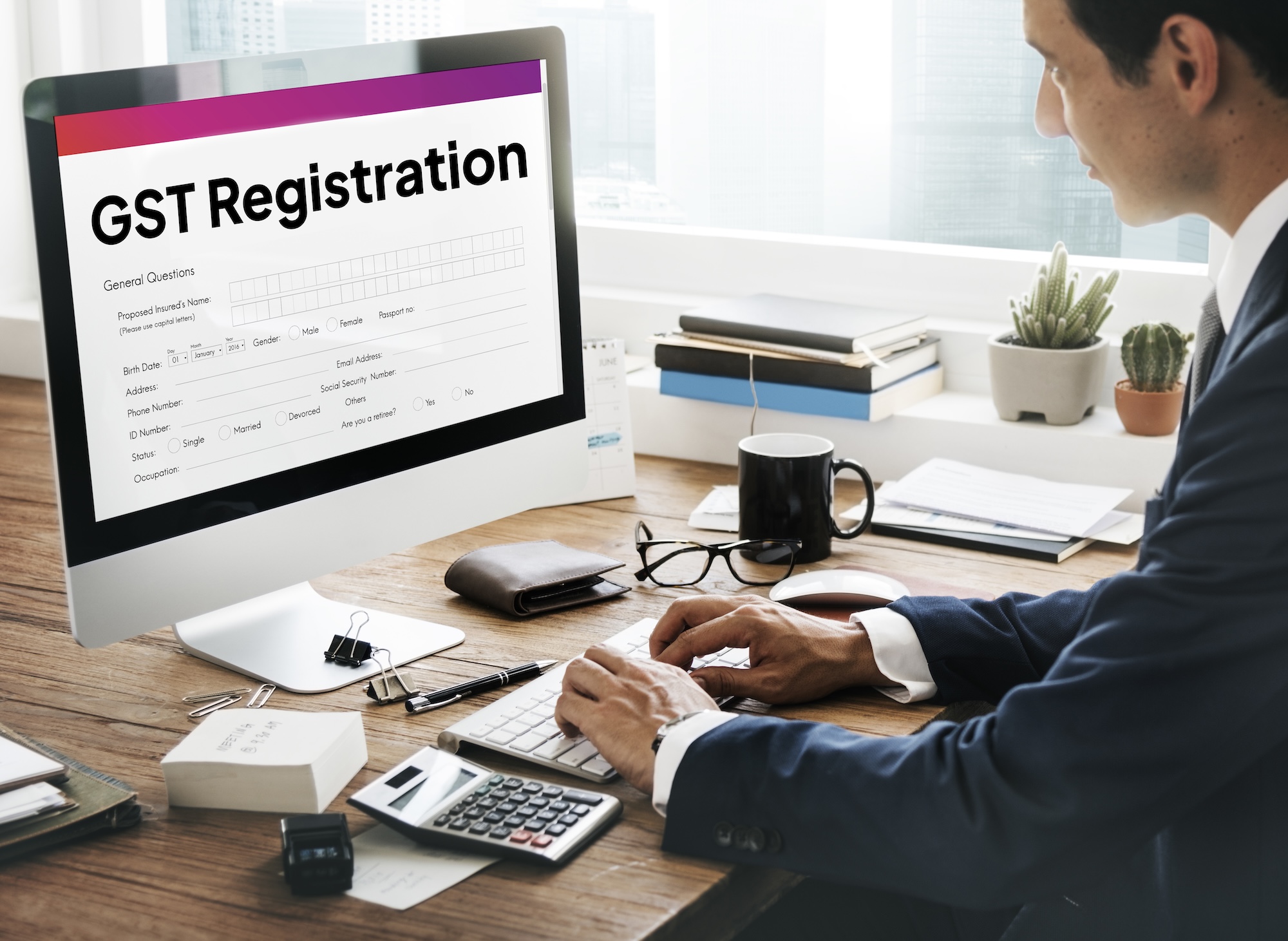 B-Wiz Partners GST registration form displayed on a computer screen while a business professional completes the application.