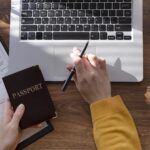 Employer reviewing a foreign employee work pass application with a passport, application form, laptop, and calculator.