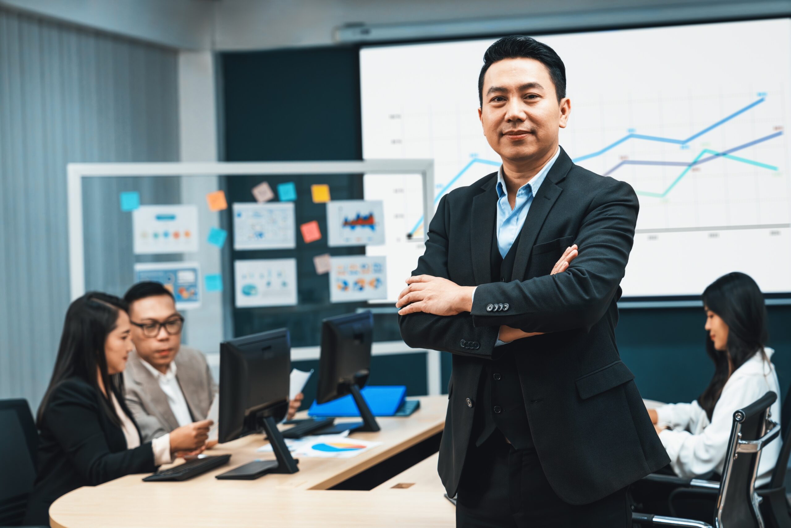 Business consultant leading a team meeting with charts and business performance data displayed on a screen.