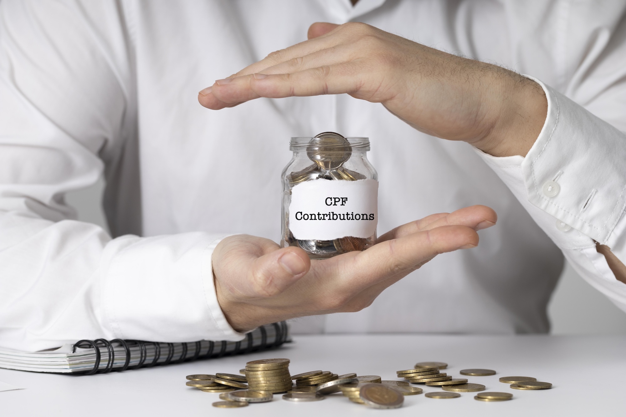 **Alt text:** Hands protecting a jar of coins labelled “CPF Contributions,” representing CPF contributions for employers in Singapore.